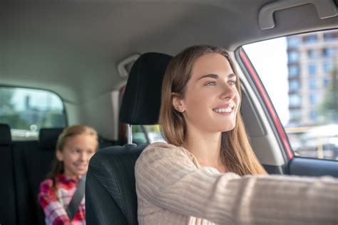 Mam Sonriente Conduciendo Con Su Hija Sentada En El Asiento Trasero