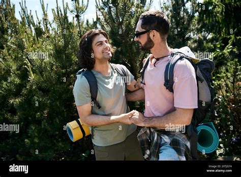 A Gay Couple Smiles And Holds Hands As They Hike Through A Summer Forest Stock Photo Alamy