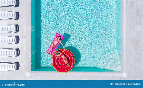 Deux Filles Sexy Dans Le Bikini Nagent Dans Une Piscine Sur Des Matelas Gonflables Image Stock