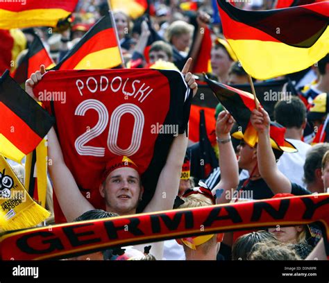 A German Supporter Stands In The Crowd And Holds Up The Jersey Of