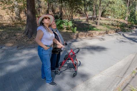 Hija Adulta Que Apoya A Su Madre Mayor Cuando La Lleva A Caminar Con Un