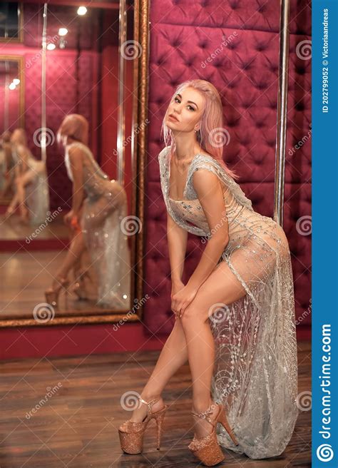 Beautiful Woman In Shining Silver Dress Posing By Pylon In Strip Night