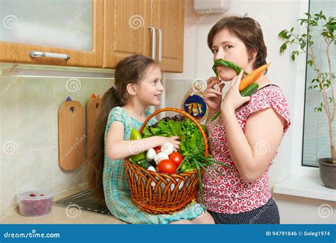 Mother And Daughter Having Fun With Basket Of Vegetables And Fresh