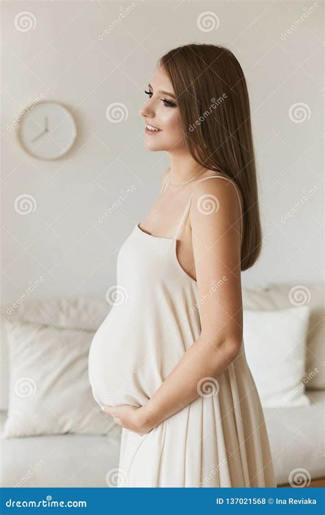 Beautiful And Sensual Brown Haired Pregnant Model Girl With Blue Eyes And With Gentle Makeup In