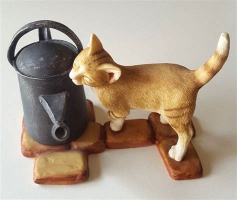 A Cat Figurine Standing Next To A Watering Can On Top Of Wooden Blocks