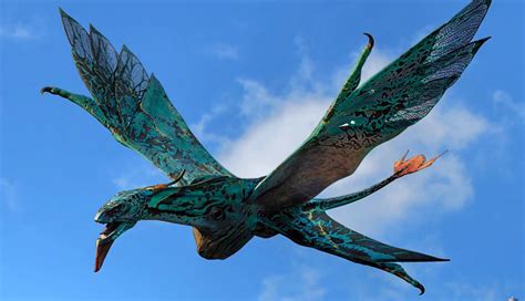 A Large Green Bird Flying Through A Blue Sky With Clouds In It S Back