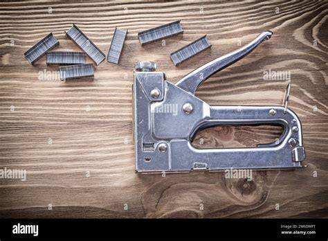 Composition Of Construction Stapler Staples On Wood Board Top View