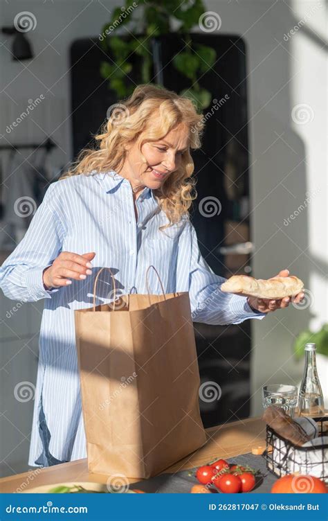 Blonde Mature Woman Unpacking A Bag After Food Shoopping Stock Image