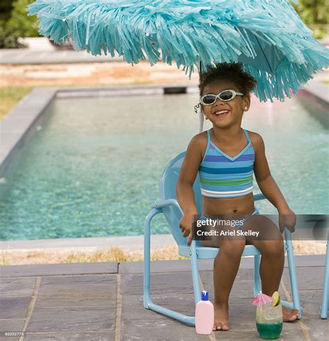 Young Girl Sitting Next To Pool In Bathing Suit High-Res Stock Photo ...