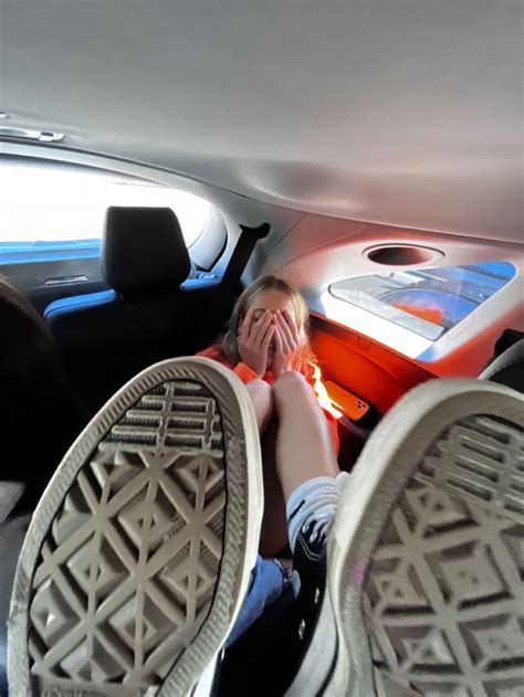 Two People Sitting In The Back Seat Of A Car With Their Feet Propped Up