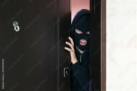 Man Burglar In Black Mask Open The Door Stealing Something From House