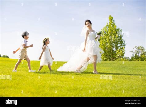 Beautiful Chinese bride walking through a park with flower girl and ... 