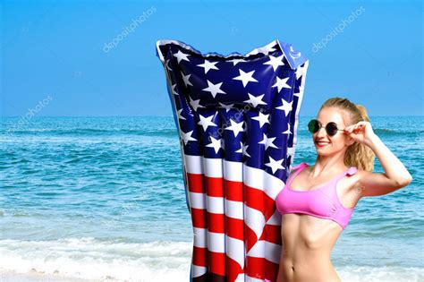 Vacaciones de verano Disfrutando de la mujer bronceadora en bikini con colchón inflable bandera
