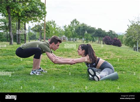 Personal Trainer Helping Young Woman Doing Splits And Stretching