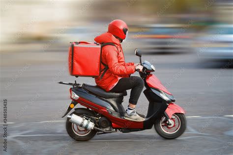 Food Delivery Moto Scooter Driver With Red Backpack Behind Back Is On