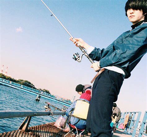 A Man Standing On A Pier Holding A Fishing Pole