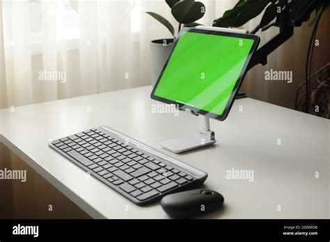 Tablet on stand with keyboard and mouse. Minimalism interior with ...