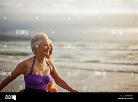 Happy Mature Women Running Along A Beach A Low Tide Stock Photo Alamy