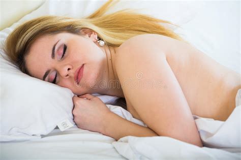 Jeune Femme Nue Se Situant Dans Le Lit Sur Les Feuilles Blanches Image