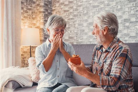 Portrait Of Two Cute And Old Seniors At Home Having Fun Together Mature Man Giving A Gift At