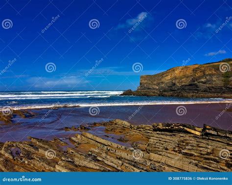 Coastal Scene With Jagged Rocks Turbulent Sea Waves And A Towering