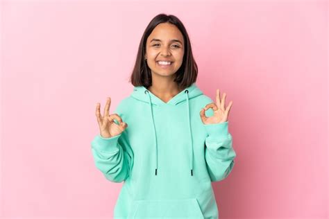 Mujer Latina Joven Aislada En La Pared Rosa Que Muestra El Signo De Ok Con Las Dos Manos Foto