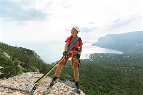 Alpinista Sobe A Montanha Em Um Cabo Vista Para A Floresta E O Mar