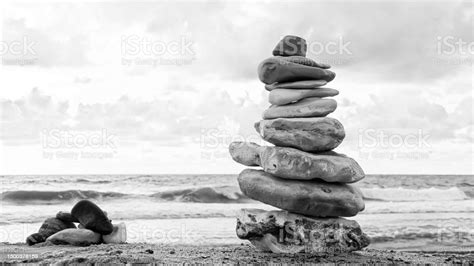 Black And White Photograph Of Rock Tower Sitting On The Beach Stock