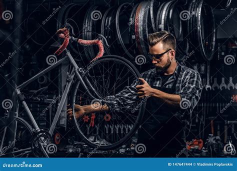 L Uomo Serio Bello In Vetri Di Protezione Sta Riparando La Bicicletta