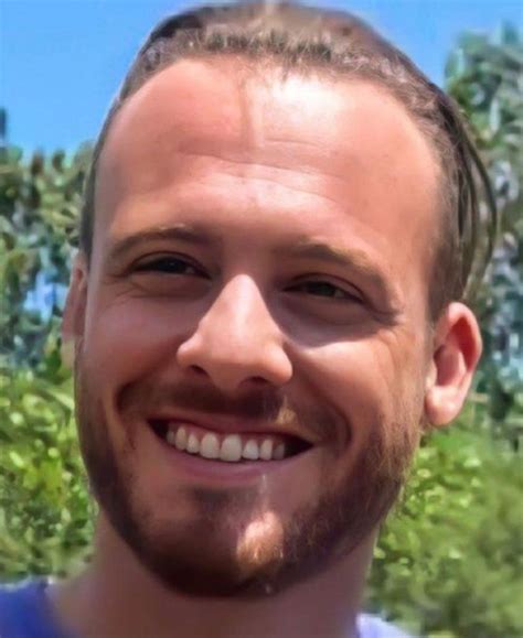 A Close Up Of A Person Smiling With Trees In The Backgroung Behind Him