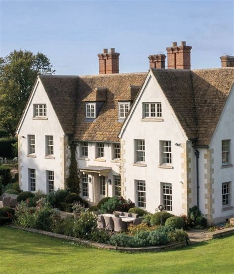 A Large White House Sitting On Top Of A Lush Green Field