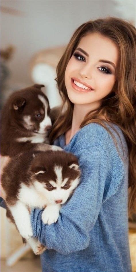 A Woman Holding Two Puppies In Her Arms