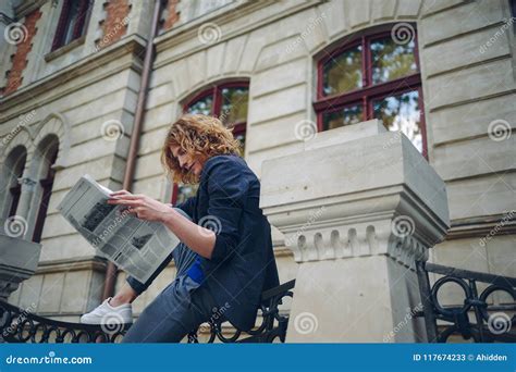 Periódico Rojizo Joven De La Lectura Del Hombre Cerca Del Edificio Del