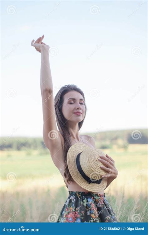 Topless Brunette Woman Covering Her Breasts With Straw Hat In The Field