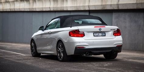 The Back End Of A White Bmw Convertible Parked In Front Of A Concrete