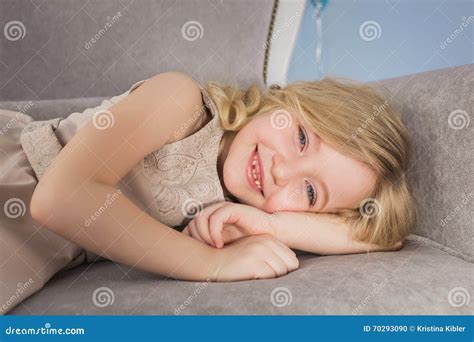 Le Portrait De La Petite Fille Blonde Se Trouve Sur Un Sofa Photo stock Image du vêtements