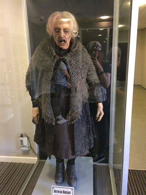 an old woman is standing in a glass case