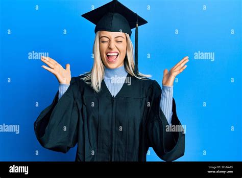 Beautiful Blonde Woman Wearing Graduation Cap And Ceremony Robe Celebrating Mad And Crazy For