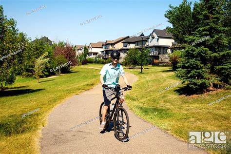 Young Man Riding His Bike Down A Path In A Residential Park Edmonton