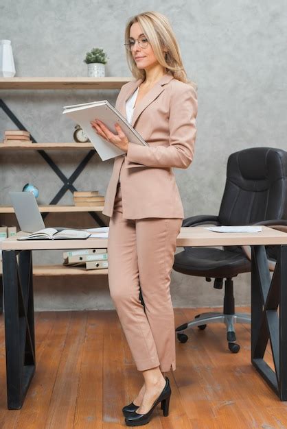Blonde jeune femme bien habillée debout au bureau lisant des documents au bureau Photo Gratuite