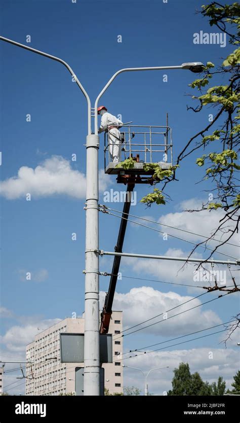 Painter In Lift Bucket Paint Street Lighting Pole At Height Man In