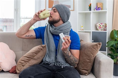 Joven Enfermo Vestido Con Bufanda Y Gorro De Invierno Sentado En El