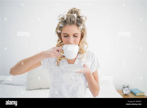 Relaxed Pretty Blonde Wearing Hair Curlers Drinking Coffee Stock Photo