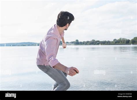 Man throwing stone water lake fun Stock Photo - Alamy