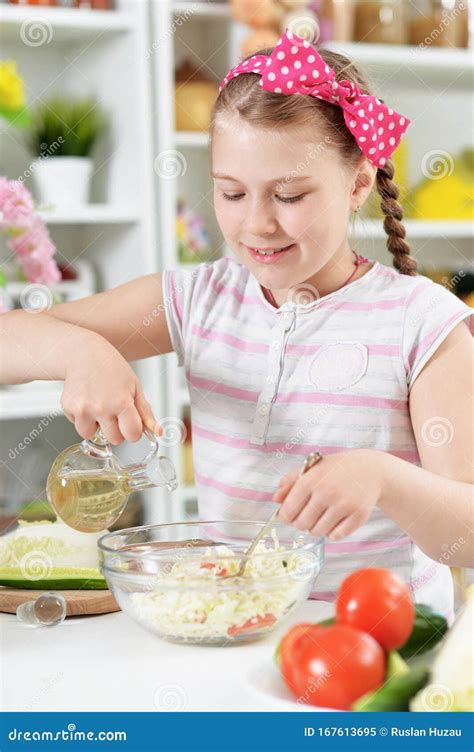 Cute Girl Preparing Delicious Fresh Salad In Kitchen Stock Image