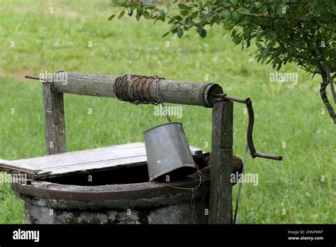 Rustic wooden water well with woodpile of firewood Stock Photo - Alamy