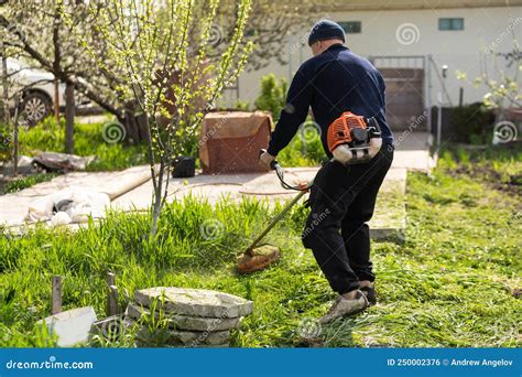 Man Mowing The Lawn In His Garden Gardener Cutting The Grass