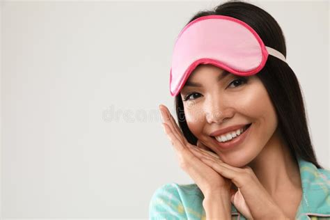 Beautiful Woman Wearing Pajamas And Sleeping Mask On Light Grey