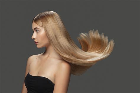 Beautiful Model With Long Smooth Flying Blonde Hair Isolated On Dark