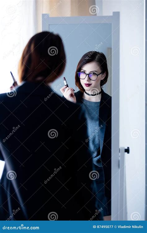 Beautiful Young Woman Standing In Front Of Mirror Holding A Lip Stock